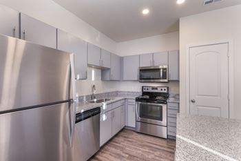 A kitchen with a stainless steel refrigerator and a stove top oven.